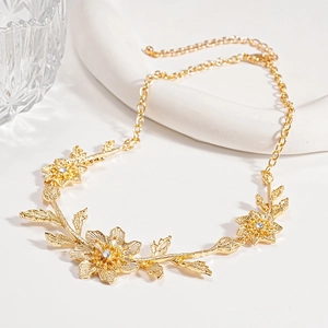 Detailed close-up of a gold-plated flower and leaf necklace with sparkling white zircons