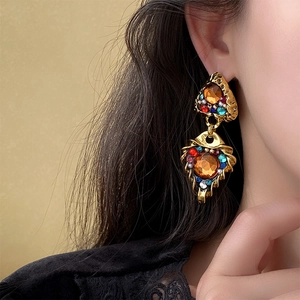 Close-up of vintage golden triangle earrings with colorful rhinestones on female model