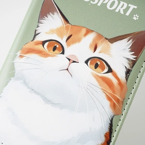 Close-up of calico cat illustration and stitching on a green PU leather passport cover