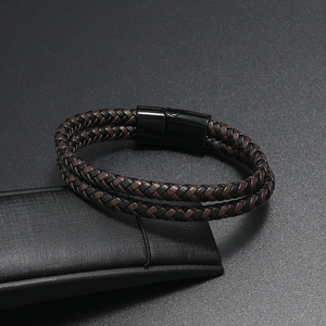Dettaglio di un bracciale in pelle intrecciata a due strati con chiusura magnetica nera