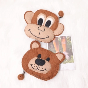 Cute animal felt coin purses in bear and monkey shapes on a soft white plush background
