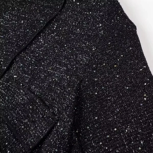 Close-up of black tweed fabric featuring shimmering silver sequins and rich texture