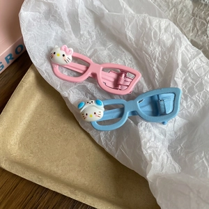 Set of two cute cartoon glasses hair clips in pink and blue colors on paper