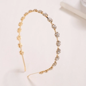 Detailed view of the gold headband featuring intricate sunflower rhinestones on beige surface
