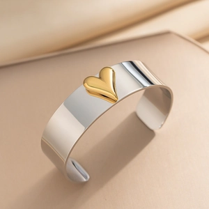 Polierter silberner C-Stahlarmreif mit 3D-Goldherz in einem minimalistischen Stil