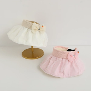Detail of girls mesh sun hat with ribbon bow and orange fruit ornament in soft colors