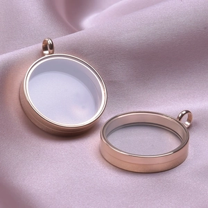 Detail of two round rose gold stainless steel lockets with glass on pink satin