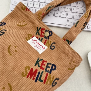 Detail of brown corduroy tote bag showing Keep Smiling print and textured fabric