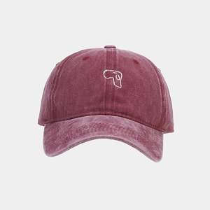 Detail of white embroidery on a washed burgundy vintage cotton baseball cap surface