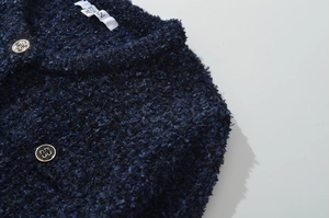 Dettaglio del colletto del cardigan in tweed blu scuro con bottoni rifiniti in oro