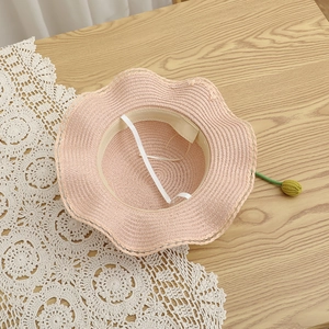 Detailed interior of a pink woven sun hat with floral charm and securing strap