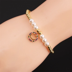Detailed macro view of a pearl bracelet featuring a colorful rhinestone smiley face charm