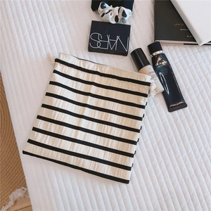 Detail of a black and white striped drawstring cotton pouch with woven cord on a quilt