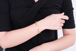 Gros plan d'un bracelet jonc fin doré pour femme orné d'une perle cylindre sertie de strass
