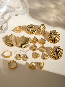 Macro detail of gold stainless steel seashell earrings and starfish rings set