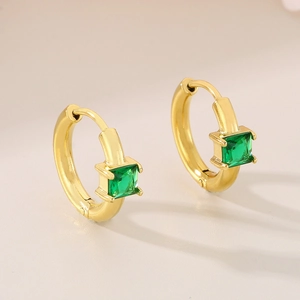 Macro view of gold hoop earrings with square-cut emerald green gemstone settings