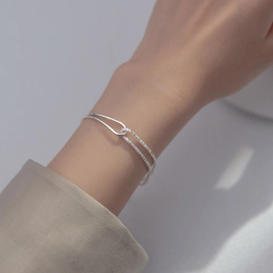 Close-up of a chic silver double-layer heart bracelet on a woman's wrist with moonstone