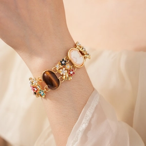 Detail of vintage gold bracelet with cameo, enamel flowers and rhinestones on wrist