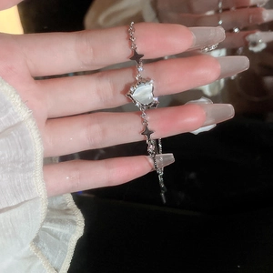 Dettaglio ravvicinato di un bracciale in argento con cuore di opale e ciondoli a stella