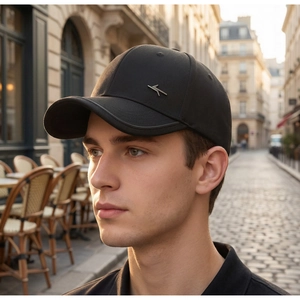 Dettaglio del cappellino da baseball nero con logo metallico in un contesto urbano