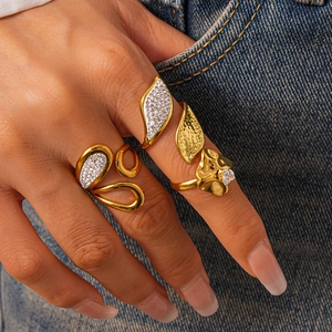 Detailed view of three gold leaf and wave rings with white zircons on denim