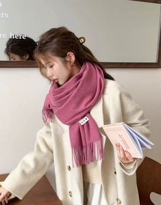 Detail of rose pink cashmere-feel scarf with tassels paired with a cream coat