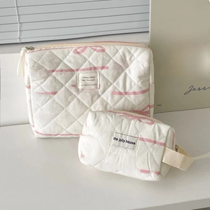 Detailed view of quilted cotton makeup bags featuring pink bow patterns and carry handle