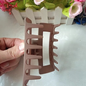 Detail of 10.5cm matte brown square hair claw clip held by hand against a desk
