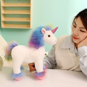 Weißes Einhorn Plüschtier mit Regenbogenmähne und Paillettenhorn in wohnlichem Ambiente