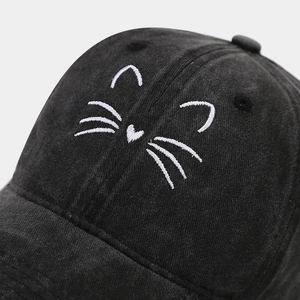 Close-up of cute cat whiskers embroidery on black corduroy baseball cap texture