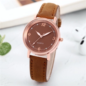 Macro shot of luminous women watch with brown dial and rose gold case on stone background