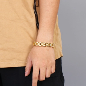 Detail of a bold golden link bracelet in watch-strap style on a male wrist