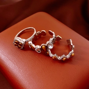 Detail view of vintage oval tiger eye rings on a premium orange leather jewelry box