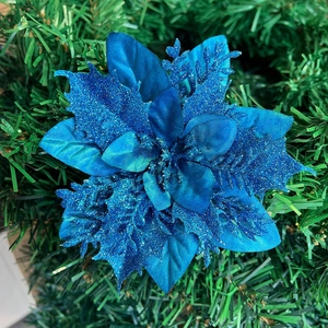 Macro shot of blue artificial Christmas flower with glitter on green pine needles