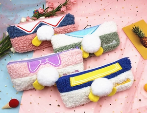 Detail showing colorful plush pencil cases with Donatella embroidery and white pom-poms
