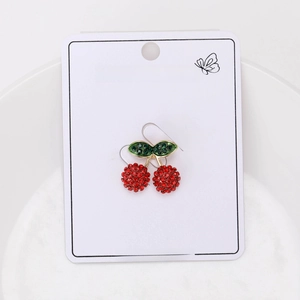 Detail view of cute cherry earrings with red and green crystals on golden metal base