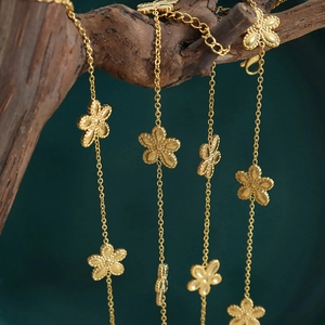 Elegant gold-plated clover flower necklace jewelry set hanging on a rustic tree branch