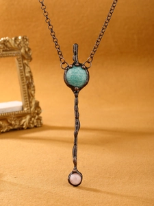Detail of vintage bronze pendant necklace featuring cyan natural stone and pink bead