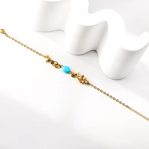 Minimalist gold chain bracelet with leaf charms and a blue oval stone centerpiece