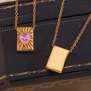 Detail showing 18K gold plated rectangular pendants with pink heart zircon on jewelry box
