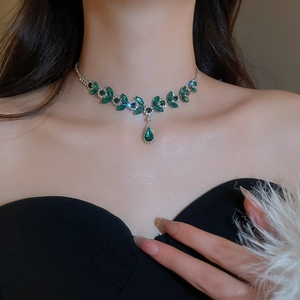 Close-up of elegant silver necklace featuring green marquise stones and teardrop pendant