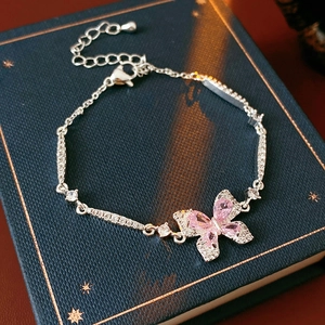 Gros plan d'un bracelet papillon argenté avec zircons roses sur un livre vintage