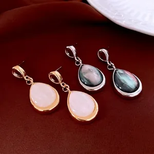 Elegant hollow teardrop shell earrings in gold and silver finish on red velvet base