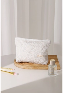 Close-up of white embossed floral canvas makeup bag with a minimalist brand label
