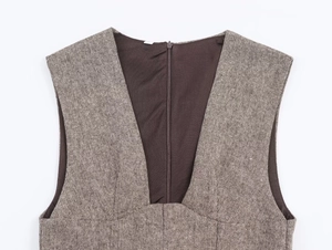 Detail of greyish-brown tweed dress featuring deep V-neckline and back zipper closure