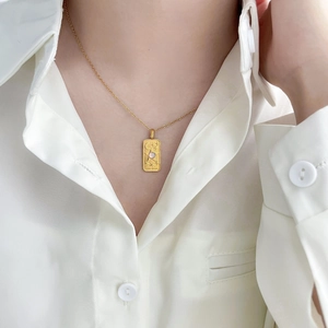 Macro view of gold tarot square pendant with The Star engraving on snake chain