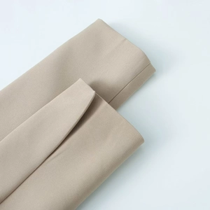 Detailed close-up of premium beige woven fabric texture for professional women's blazer