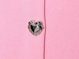 Close-up of the silver heart-shaped button on pink knitted fabric showing texture
