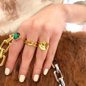 Dreiteiliges Goldring-Set mit grünem Edelstein und unregelmäßigen Wellendesigns am Modell