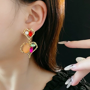 Dettaglio di orecchini vintage a cuore con gemme colorate e strass di cristallo